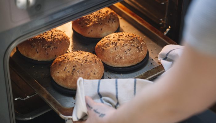 Woman taking homemade vegan burger rolls out of oven